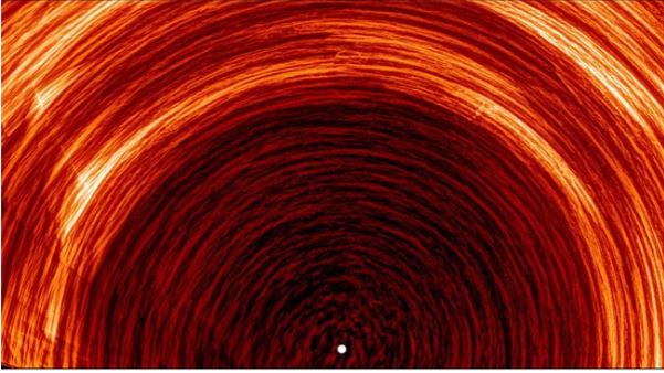 [تصویر: مجموعه‌ای از حلقه‌های قرمز رنگ که بر فراز یک نقطه نورانی سفید در وسط تصویر قوس زده‌اند]